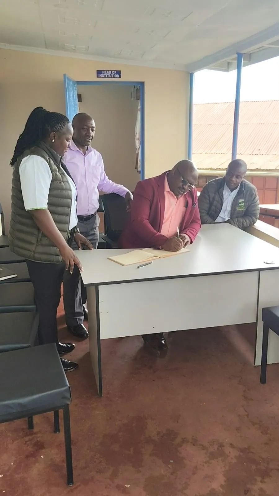 School leaders signing for donated office furniture alongside Tai Sacco staff