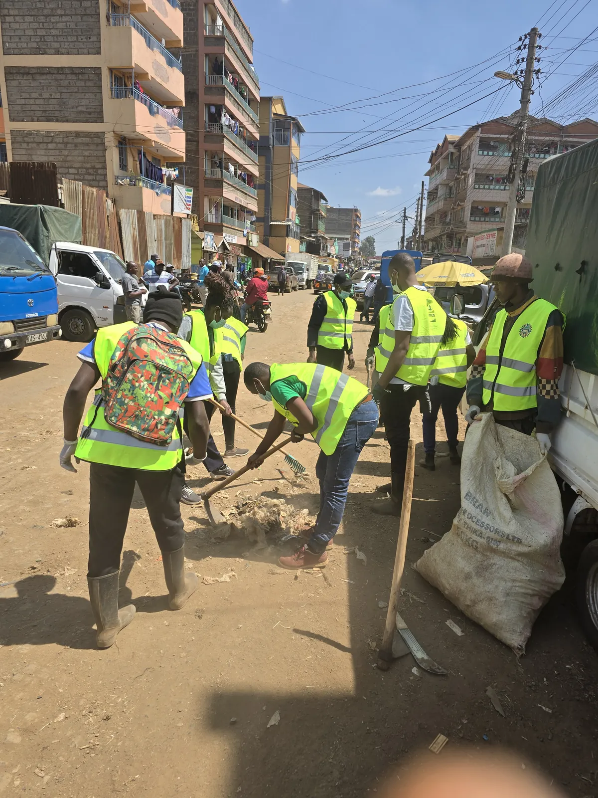 Volunteers shovelling rubbish into sacks along a busy town street